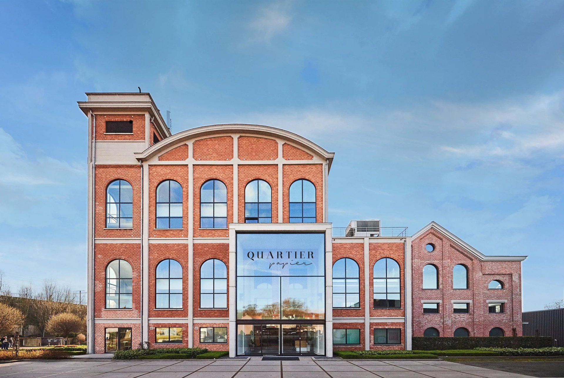 Quartier Papier — historic red-brick venue with tall arched windows and the QUARTIER papier sign above the glass entrance.